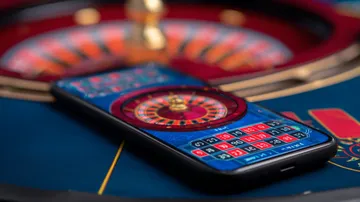 A man celebrating a winning moment on his laptop while gaming symbols float around him, capturing the excitement of SPINARA games.